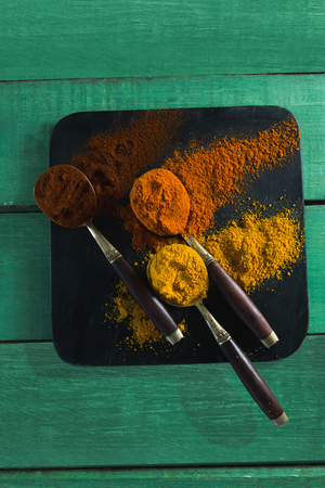 Various type of spices in spoon on wooden tableの写真素材