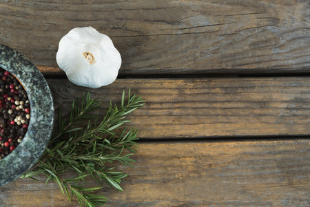 Overhead of garlics, rosemary and mix peppercorns on chopping boardの写真素材