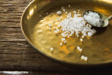 Close-up of salt in spoon and plate on wooden tableの写真素材