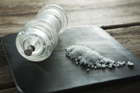 Close-up of salt shaker and salt on black slate plateの写真素材