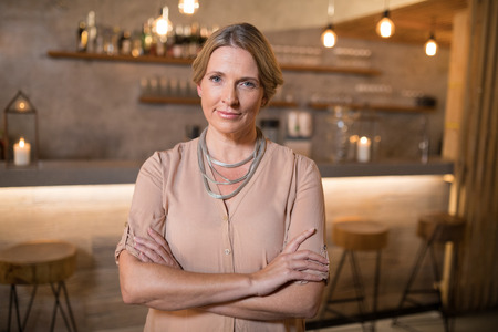 Portrait of beautiful woman standing with arms crossed in restaurantの写真素材