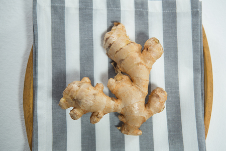 Directly above view of fresh ginger on striped napkin in plate over white backgroundの写真素材