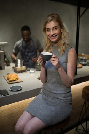 Portrait of beautiful woman having coffee at counter in cafeの写真素材