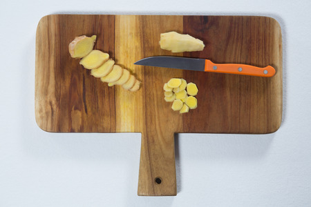 Directly above view of chopped gingers and knife on wooden cutting board over white backgroundの写真素材