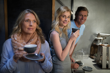 Portrait of happy friends having coffee at cafe counterの写真素材