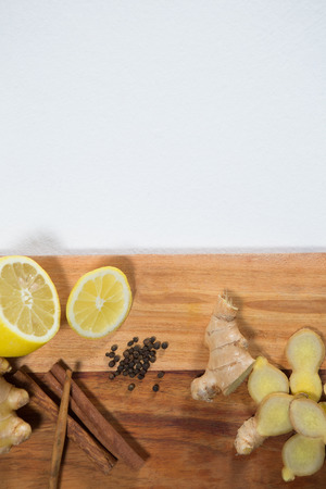 Overhead view of lemon and various spices on wooden serving board against white backgroundの写真素材