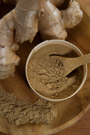 Directly above view of ginger with powder in plate on wooden serving boardの写真素材