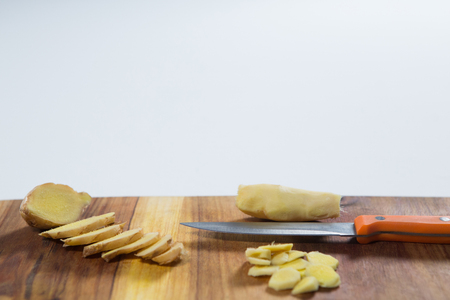 Close up of knife and fresh chopped gingers on cutting board against white backgroundの写真素材