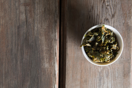 Overhead view of dried kale in bowl on wooden tableの写真素材