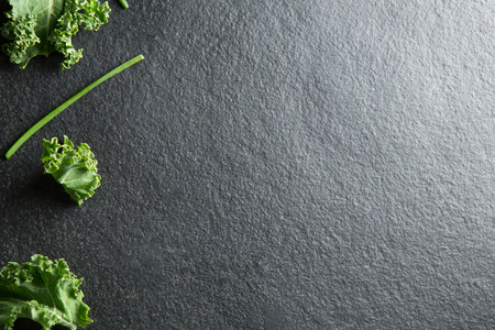 Overhead view of fresh kale on slateの写真素材
