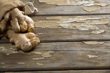 Close up of fresh gingers and burlap on weathered wooden tableの写真素材