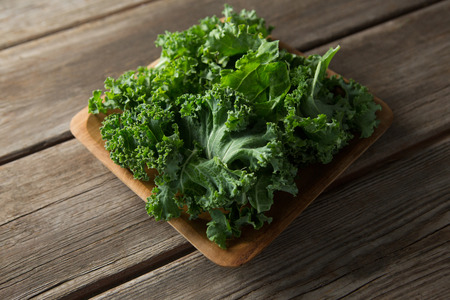 Close up high angle view of fresh kale in bowl on wooden table