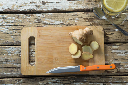Overhead view of fresh gingers on cutting board by tea over weathered wooden tableの写真素材