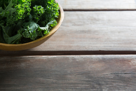 Close-up of fresh kale in bowl on wooden tableの写真素材