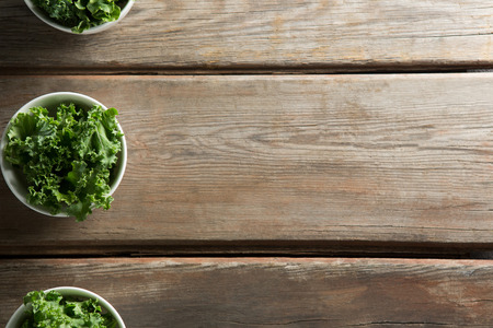 Kale arranged in bowls on brown wooden vtableの写真素材