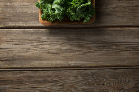 Overhead view of fresh kale in bowl on wooden tableの写真素材
