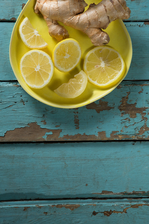 Overhead view of lemon and ginger in plate on textured wooden tableの写真素材