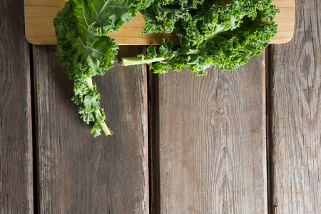 Cropped overhead view of fresh kale on cutting board at wooden tableの写真素材