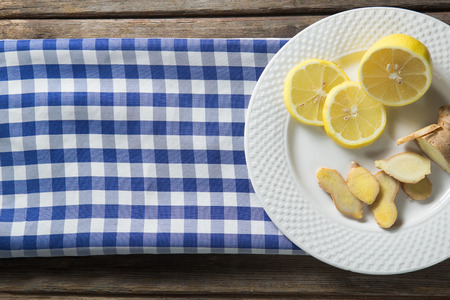 Overhead view of lemon and ginger in plate with checked patterned napkin on tableの写真素材