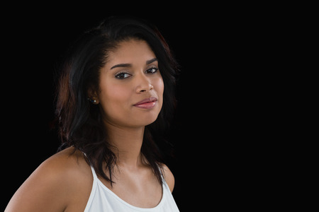 Portrait of young woman standing against black backgroundの写真素材