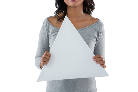 Mid section of young woman holding triangle shaped placard against white backgroundの写真素材