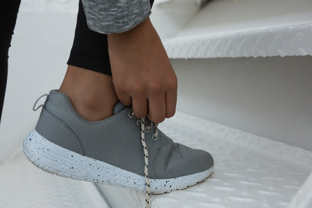 Low section of female athlete tying shoelace on stairsの写真素材