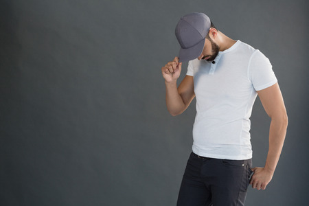 Handsome man posing with cap against grey backgroundの写真素材