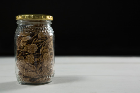 Wheat flakes in glass jar on tableの写真素材