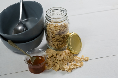 Close-up of breakfast cereals and jar of honey on tableの写真素材