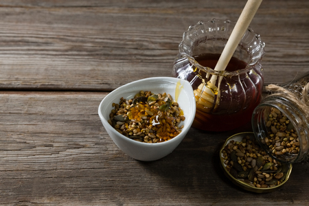Close-up of breakfast cereals and jar of honey on wooden tableの写真素材