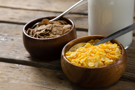 Wheat flakes and wheaties cereal in bowl on wooden table