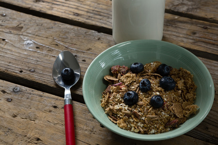 Muesli and blueberries in bowl on wooden table