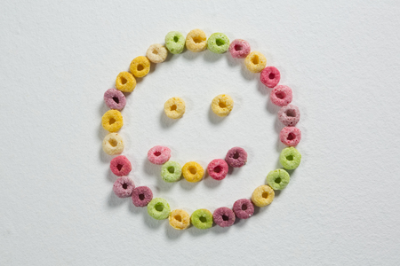 Froot loops forming a smiley face on white backgroundの写真素材