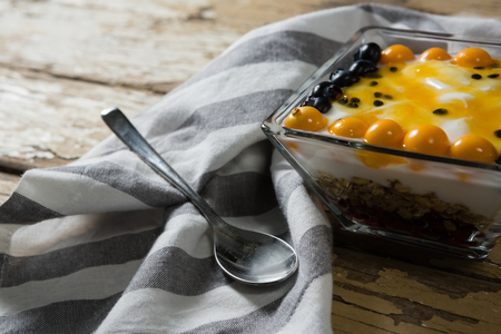 Yogurt with blueberries and golden berries in bowl on wooden tableの写真素材