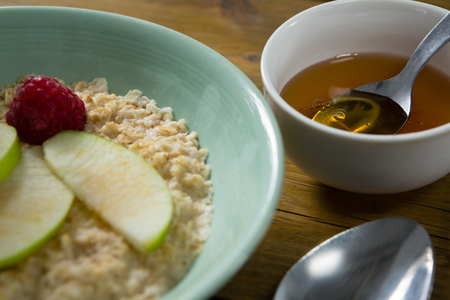 Close-up of fruit cereal and honey on wooden tableの写真素材