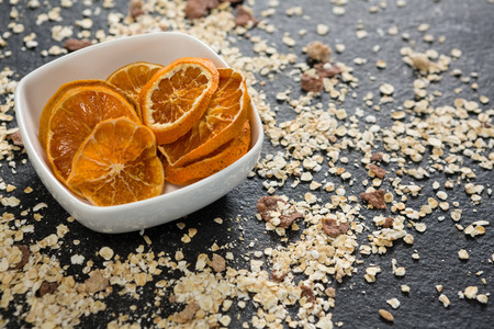 Bowl of dried orange slices and breakfast cereals on tableの写真素材