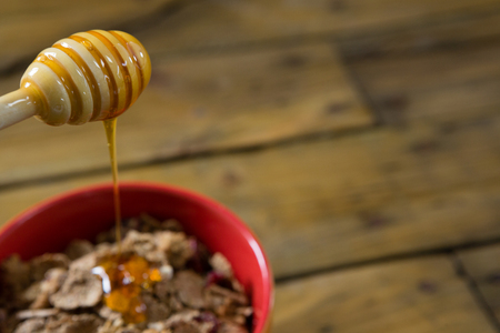 Close-up of honey pouring into a cereal bowl