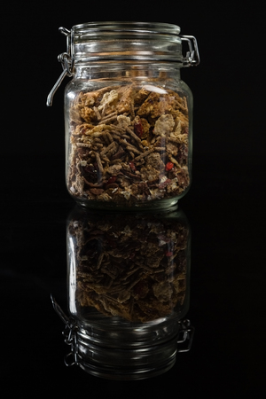Mixed breakfast cereals in glass jar on black backgroundの写真素材