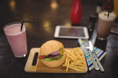 High angle view of fresh burger and fries served on table at cafeの写真素材