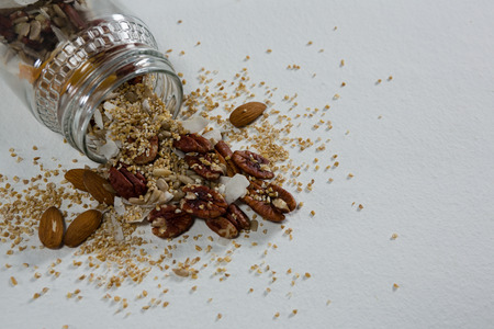 Dried fruits spilling out of bottle on white backgroundの写真素材