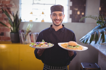 Portrait of smiling young waiter serving fresh food at coffee shopの写真素材