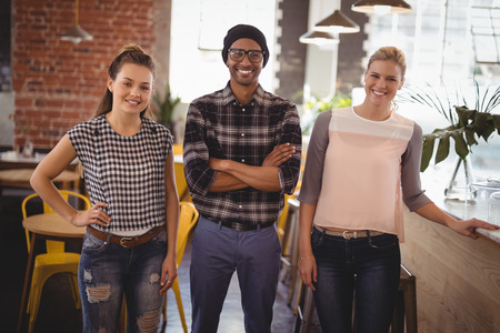 Portrait of smiling young friends standing at coffee shopの写真素材