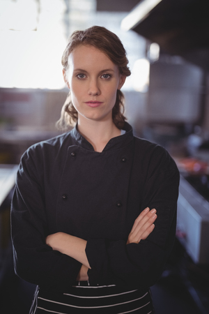 Portrait of confident young female barista standing with arms crossed at coffee shopの写真素材