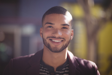 Close up of smiling young man at coffee shop on sunny dayの写真素材