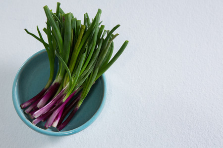 Overhead of scallions in bowl on white backgroundの写真素材