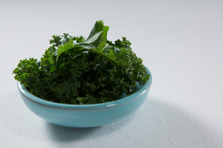 Mustard greens in bowl on white backgroundの写真素材