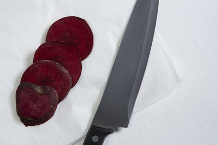 Close-up of sliced beetroots and knife on white background