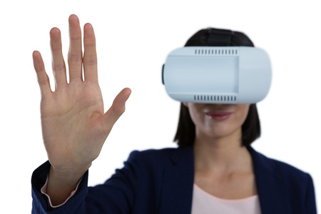 Businesswoman gesturing while using virtual reality headset against white background
