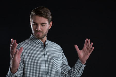 Man pretending to hold an invisible object against black backgroundの写真素材