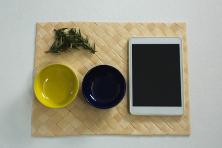 Close-up of rosemary and empty bowls with digital tablet on place matの写真素材
